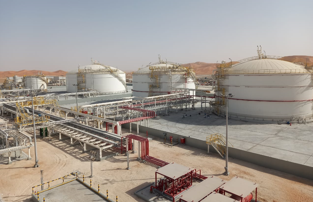 Industrial tanks and pipelines in a desert-based oil refinery, showcasing large storage tanks and infrastructure.